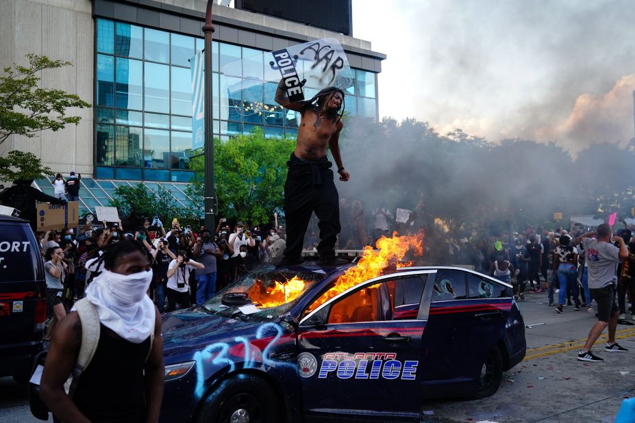 A man stands on top of a burning police car during a protest outside the CNN Center in Atlanta on May 29.