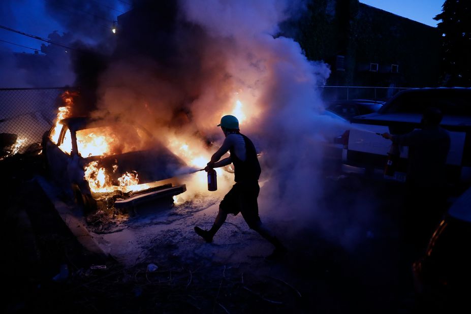 People in Minneapolis attempt to extinguish burning cars on May 29.