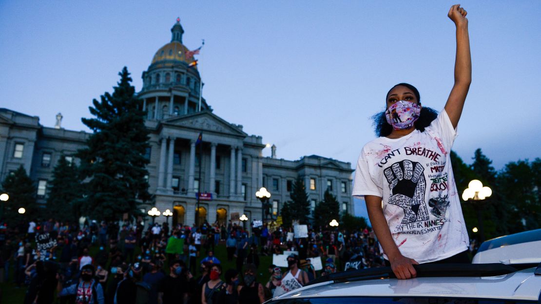 A woman wearing a mask protests near the Colorado state capitol in Denver.