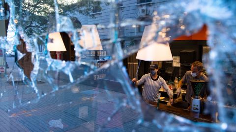 Workers clean up damaged businesses Saturday after a night of protests in Louisville, Kentucky.