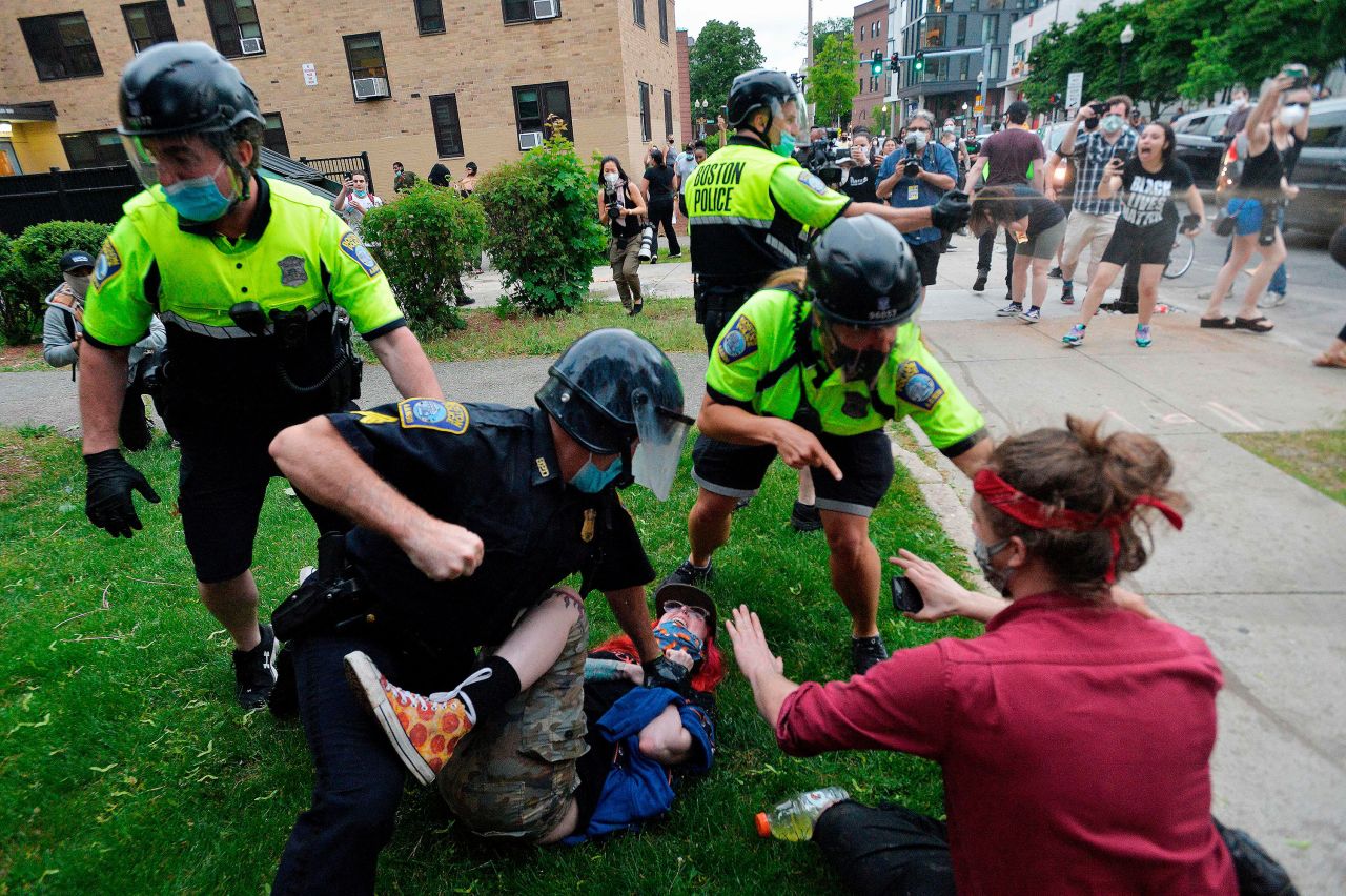 A police officer in Boston holds down a protester while another officer uses pepper spray on May 29.