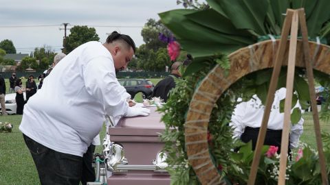 Jesse Macias, Guadalupe Ortiz-Sandoval's son, kisses his mother's coffin as others watch from a distance at Forest Lawn Cypress cemetery in California. 