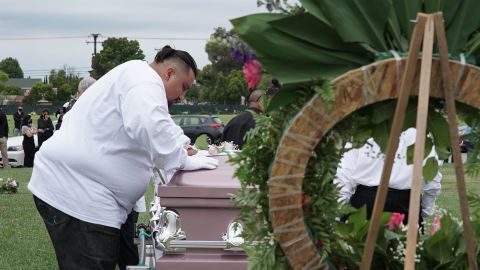 Jesse Macias, Guadalupe Ortiz-Sandoval's son, kisses his mother's coffin as others watch from a distance at Forest Lawn Cypress cemetery in California.