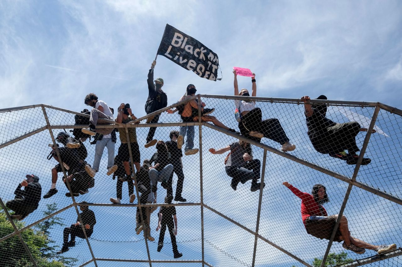 People gather on top of a baseball backstop during a protest in Los Angeles on May 30.