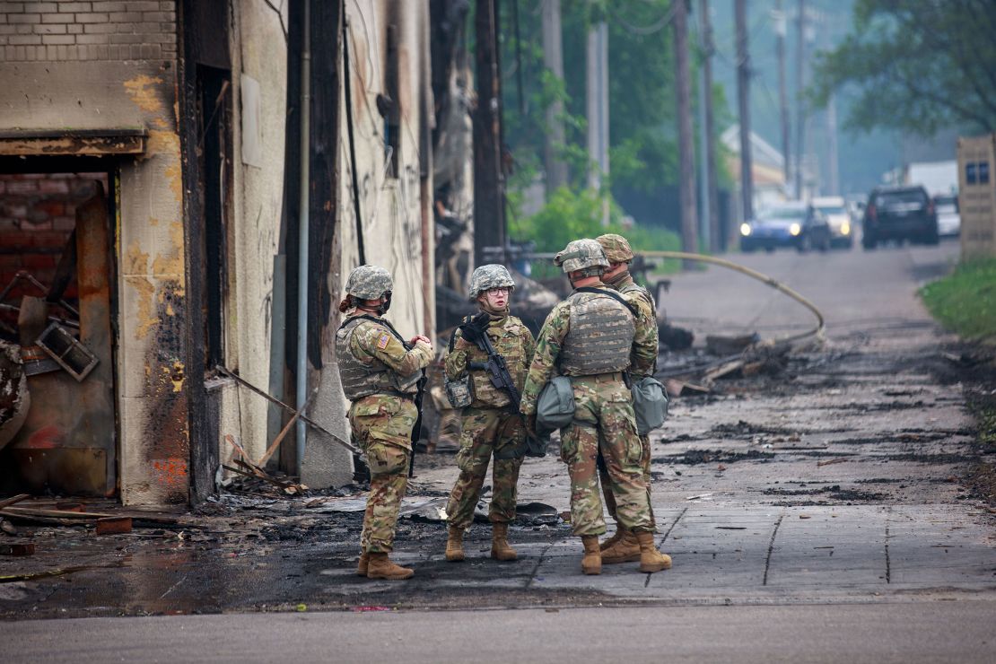 Minnesota National Guard soldiers patrol a burned street in Minneapolis. 