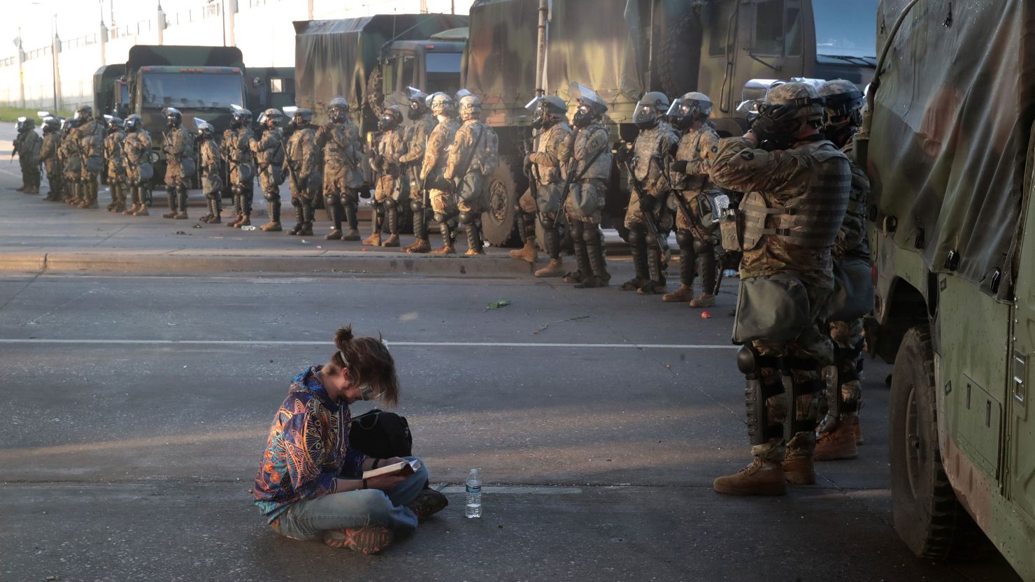 A women reads a bible in front of a line of National Guardsmen as the 8pm curfew approaches during protests sparked by the death of George Floyd while in police custody on May 29, 2020 in Minneapolis, Minnesota. Earlier today, former Minneapolis police officer Derek Chauvin was taken into custody for Floyd's death. Chauvin has been accused of kneeling on Floyd's neck as he pleaded with him about not being able to breathe. Floyd was pronounced dead a short while later. Chauvin and 3 other officers, who were involved in the arrest, were fired from the police department after a video of the arrest was circulated.