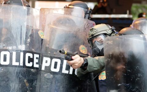 A police officer shoots rubber bullets at protesters who were throwing rocks and water bottles during a demonstration in Miami on May 30.