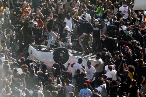 Protesters jump on an overturned car near the Municipal Services Building in Philadelphia on May 30.