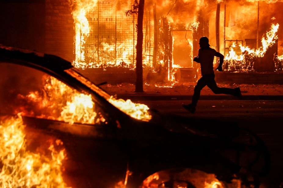 A protester runs past burning cars and buildings in St. Paul on May 30.