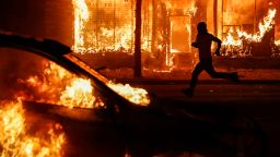 A protester runs past burning cars and buildings on Chicago Avenue, on Saturday, May 30, in St. Paul, Minnesota.