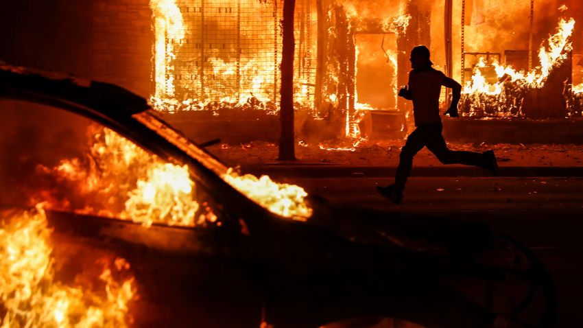 A protester runs past burning cars and buildings on Chicago Avenue, on Saturday, May 30, in St. Paul, Minnesota.