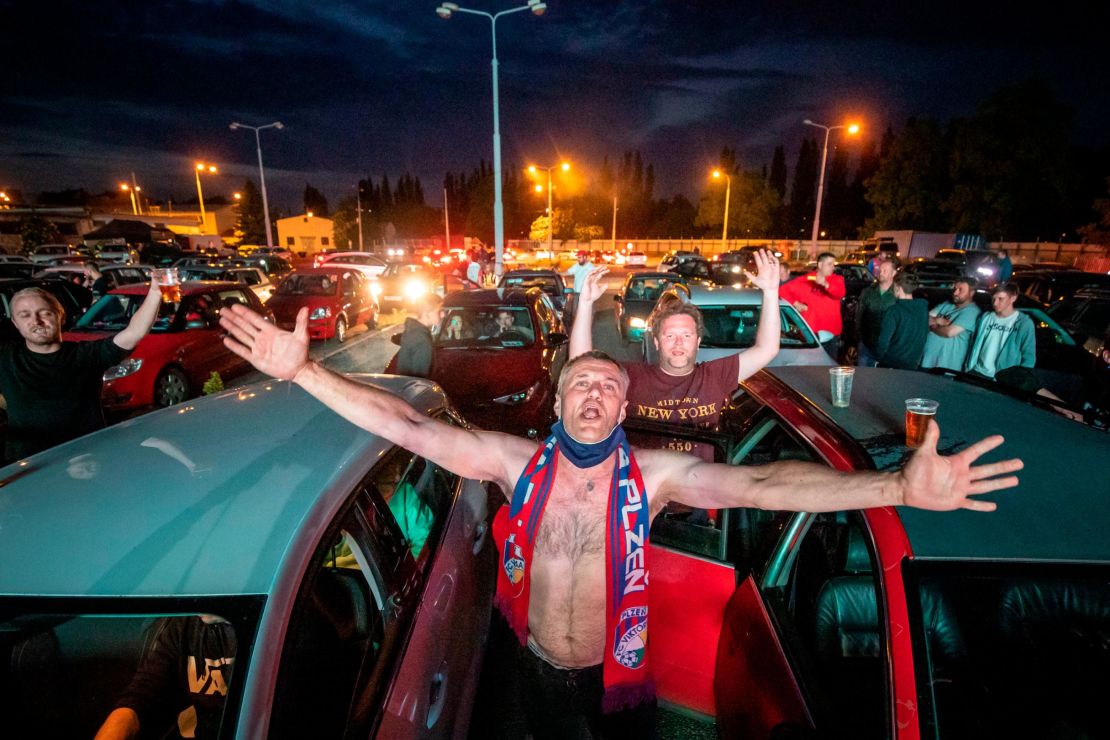 Fans cheer as they watch the Czech first division football match between FC Viktoria Plzen and AC Sparta Praha at a drive-in movie theater in Plzen, Czech Republic.