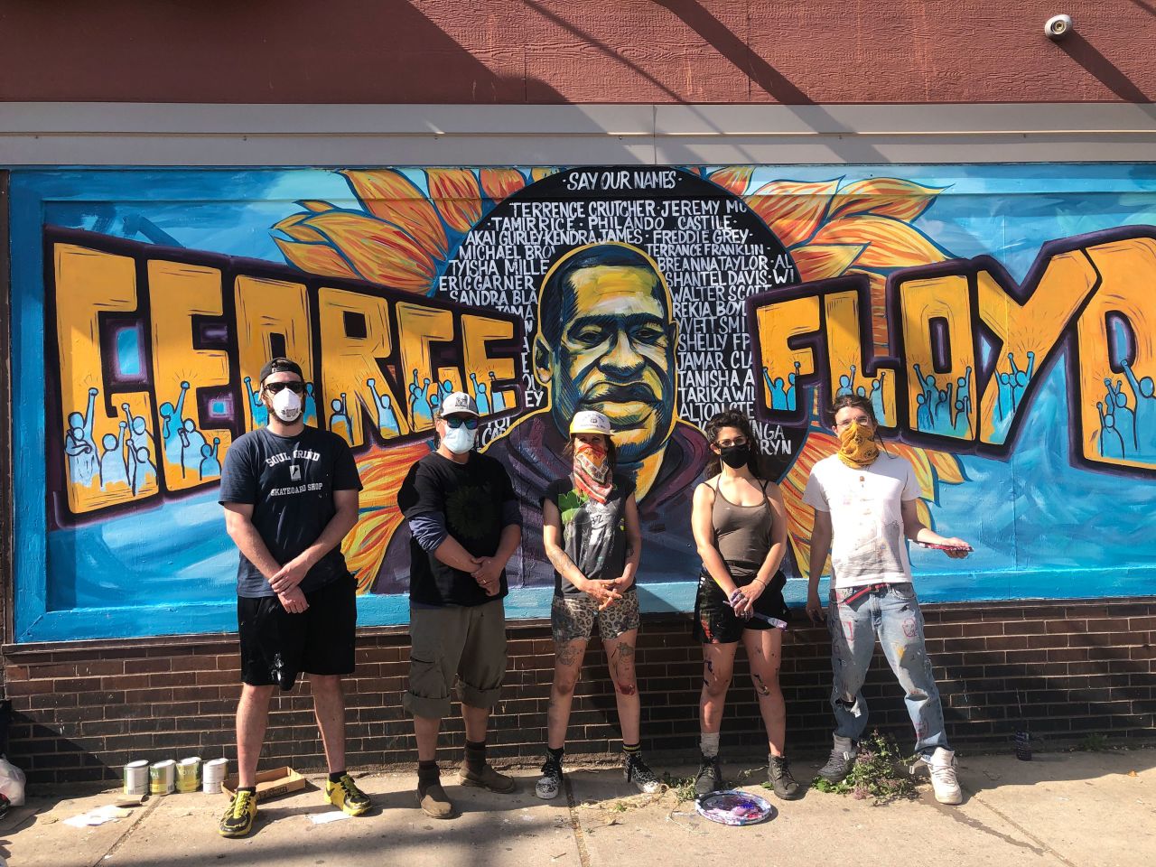 The artists stand in front of the George Floyd memorial mural that they painted in Minneapolis. From left to right: Niko Alexander, Cadex Herrera, Greta McLain, Xena Goldman, Pablo Helm Hernandez.