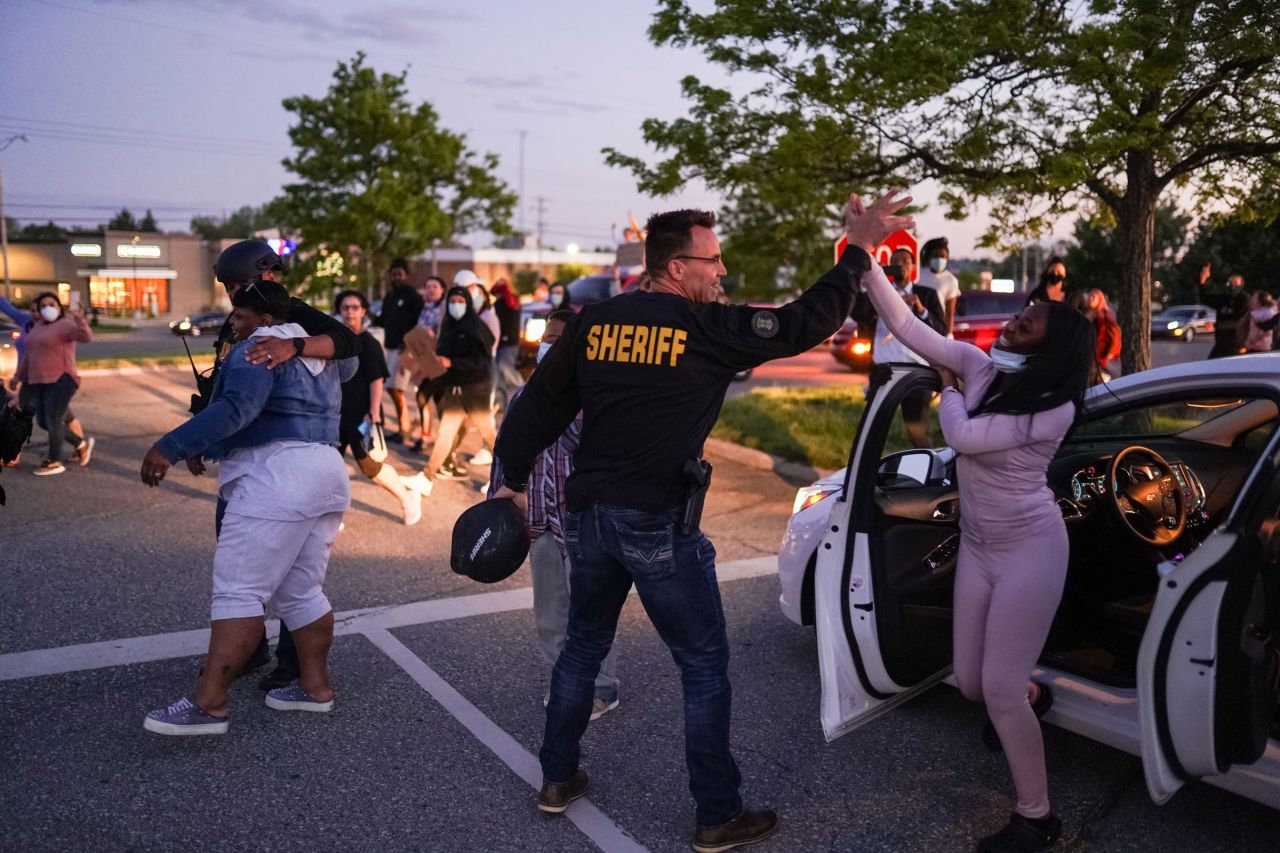 Genesee County Sheriff Chris Swanson high-fives a woman who called his name as he marches with protesters in Flint, Michigan, on May 30.