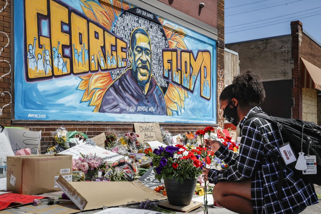 Malaysia Hammond, 19, places flowers at a memorial mural for George Floyd at the corner of Chicago Avenue and 38th Street, Sunday, May 31, 2020, in Minneapolis. 