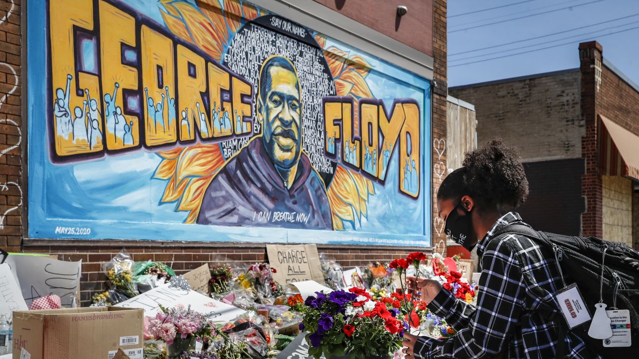 Malaysia Hammond, 19, places flowers at a memorial mural for George Floyd at the corner of Chicago Avenue and 38th Street, Sunday, May 31, 2020, in Minneapolis. 