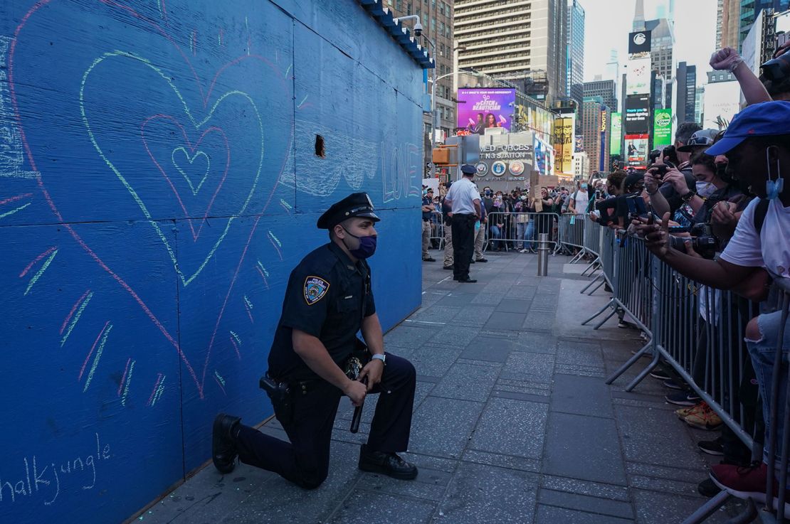 A New York City police officer takes a knee during a demonstration by protesters in Times Square.