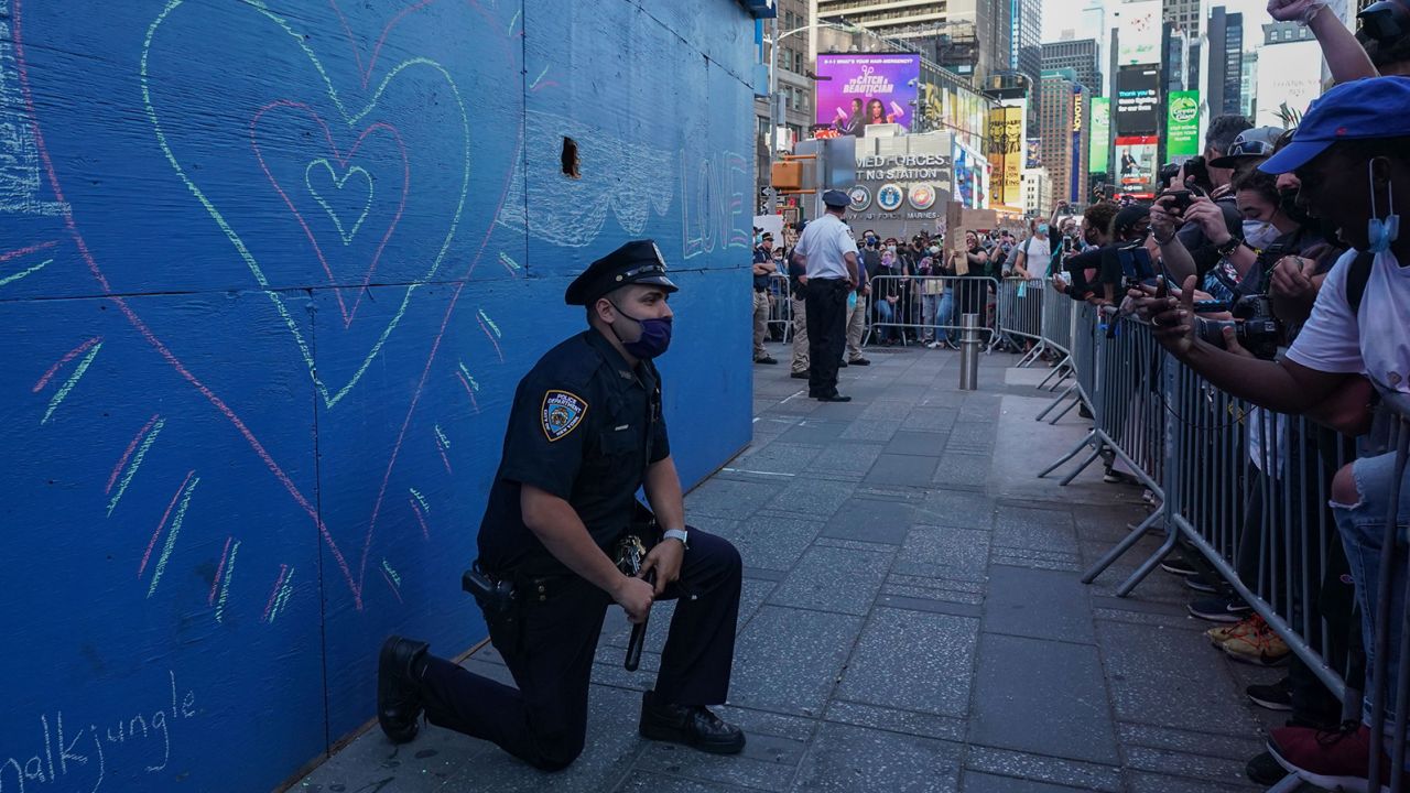 A New York City police officer takes a knee during a demonstration by protesters in Times Square.