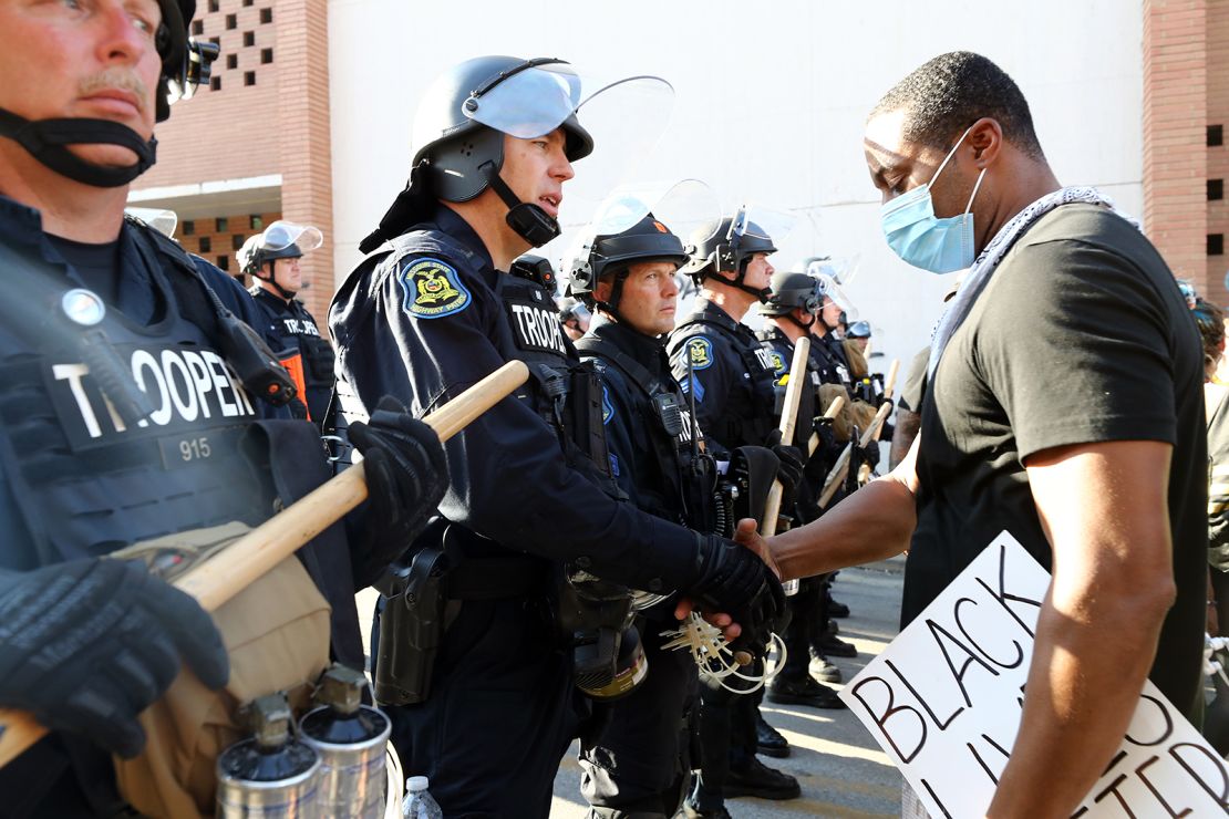 A demonstrator and police officer shake hands in Kansas City, Missouri.
