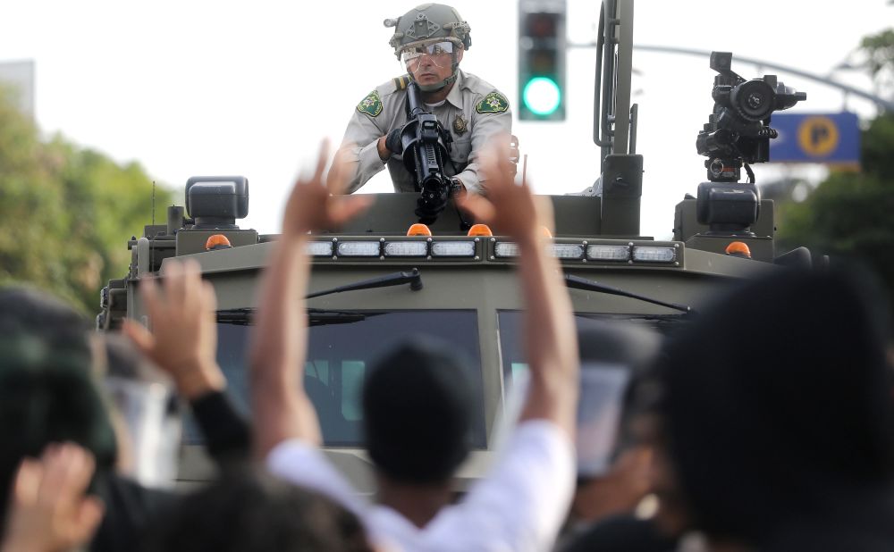 A police officer aims a nonlethal weapon as protesters raise their hands in Santa Monica, California, on May 31.
