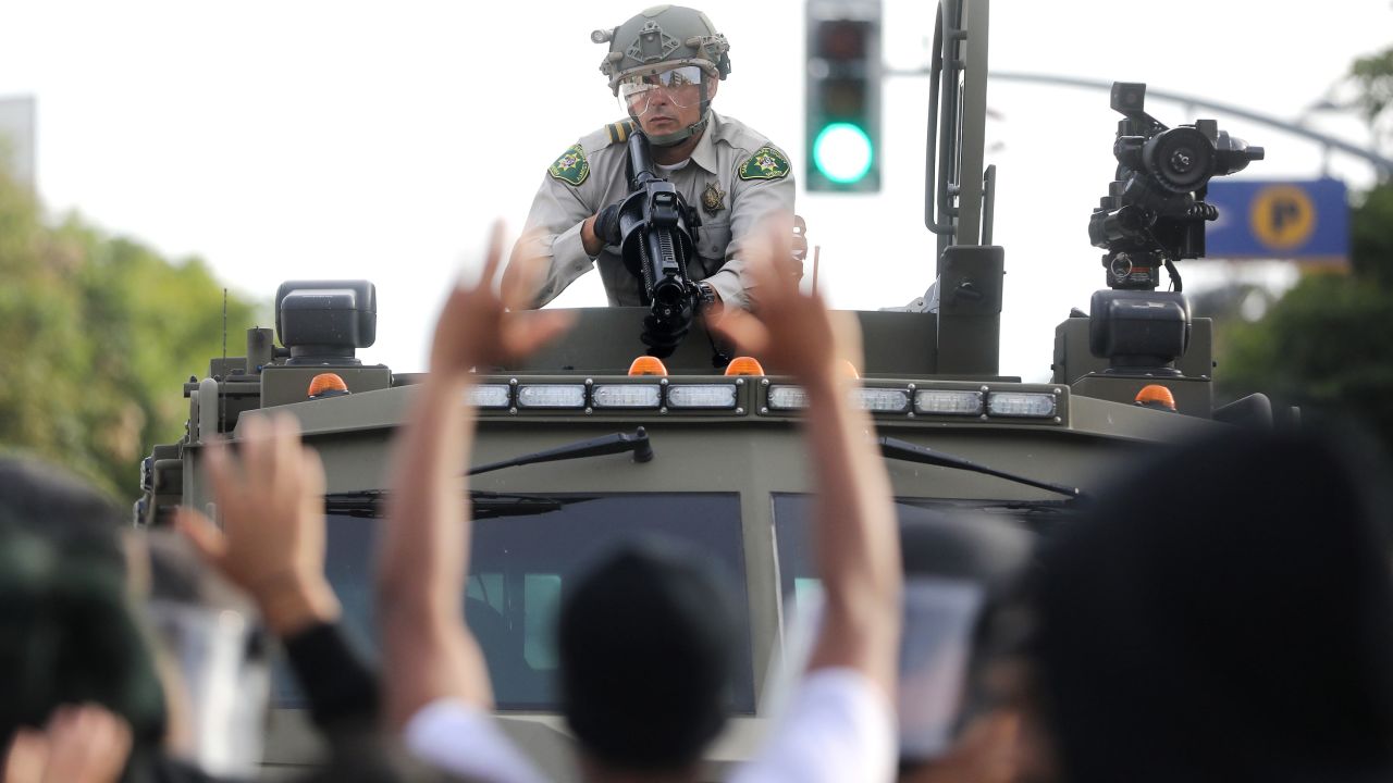 A police officer aims a nonlethal weapon as protesters raise their hands during demonstrations in Santa Monica, California, on May 31.