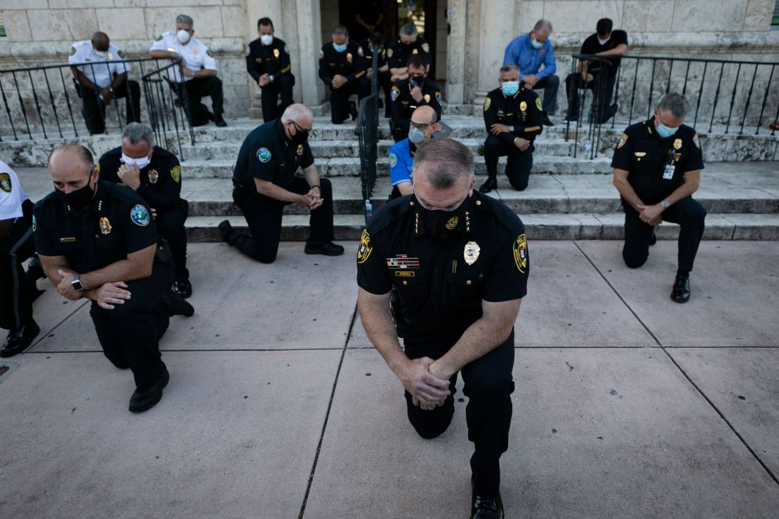 Police officers kneel during a rally in Coral Gables, Florida, on May 30, 2020 in response to the death of George Floyd.