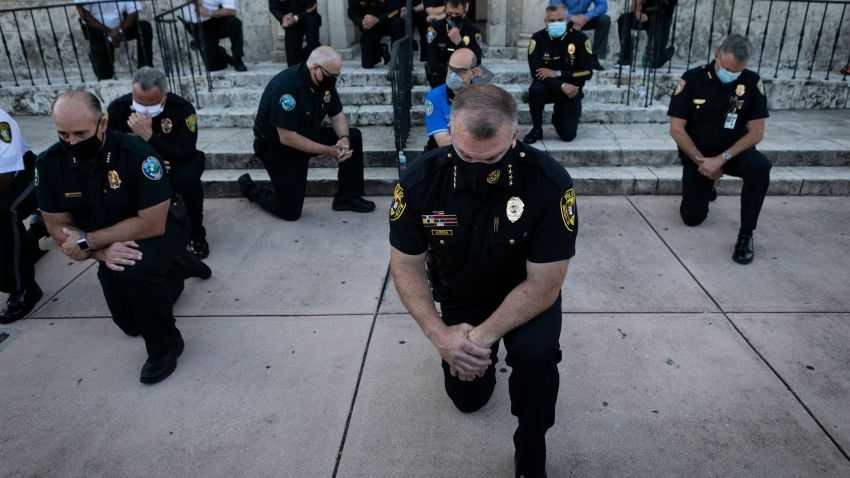 TOPSHOT - Police officers kneel during a rally in Coral Gables, Florida on May 30, 2020 in response to the recent death of George Floyd, an unarmed black man who died while being arrested and pinned to the ground by a Minneapolis police officer. - Clashes broke out and major cities imposed curfews as America began another night of unrest Saturday with angry demonstrators ignoring warnings from President Donald Trump that his government would stop violent protests over police brutality "cold." (Photo by Eva Marie UZCATEGUI / AFP) (Photo by EVA MARIE UZCATEGUI/AFP via Getty Images)