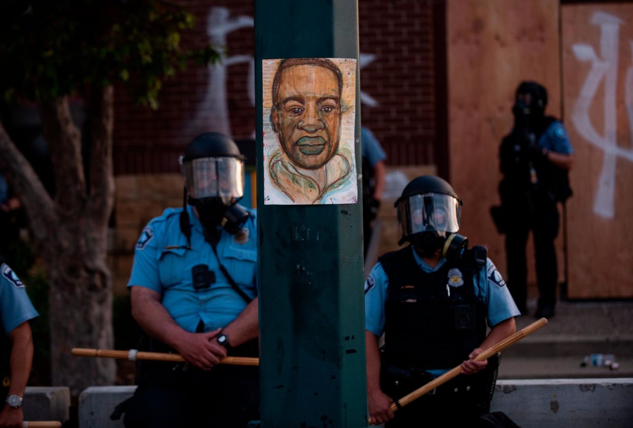  A portrait of George Floyd hangs on a street light pole as police officers stand guard at the Third Police Precinct during a face off with a group of protesters in Minneapolis, Minnesota.