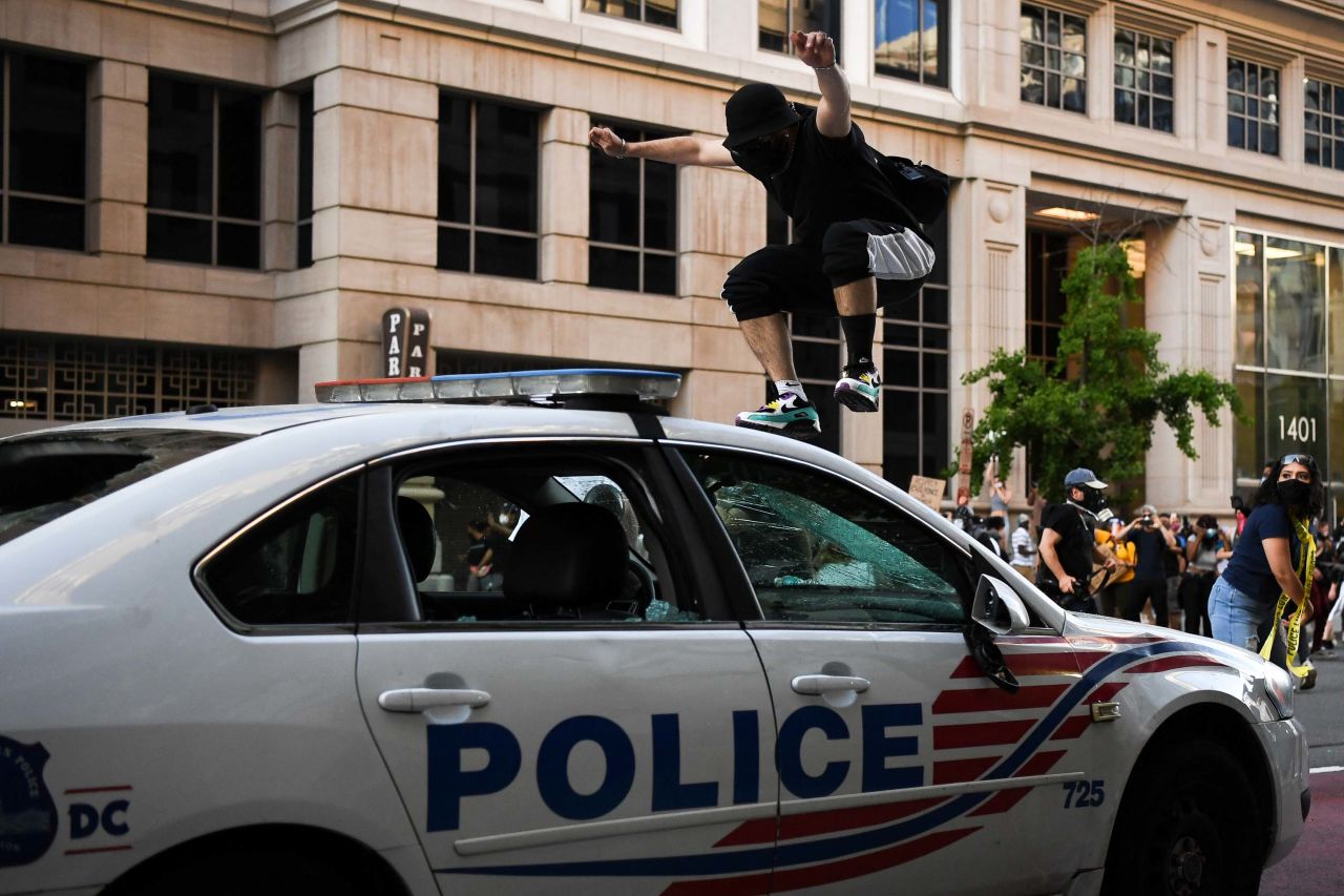A demonstrator jumps on a police car in Washington, DC, on May 31.