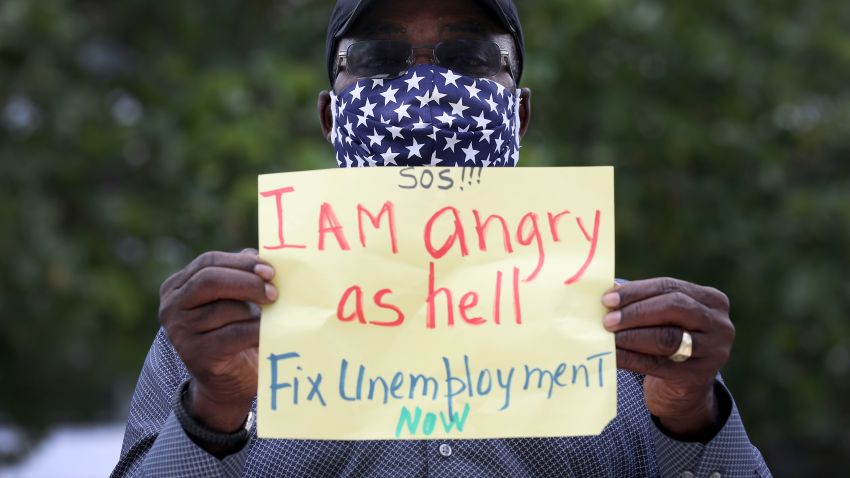MIAMI BEACH, FLORIDA - MAY 22: Odirus Charles holds a sign that reads, ' I Am angry as hell Fix Unemployment Now,' as he joins others in a protest on May 22, 2020 in Miami Beach, Florida. Unemployed hospitality and service workers who have not received unemployment checks held the protest demanding Florida Governor Ron DeSantis fix the unemployment system and send out their benefits. Since the closure of all non-essential businesses due to the coronavirus pandemic, hundreds of thousands of hospitality workers across Florida find themselves out of work. Florida's unemployment system has not worked reliably. (Photo by Joe Raedle/Getty Images)