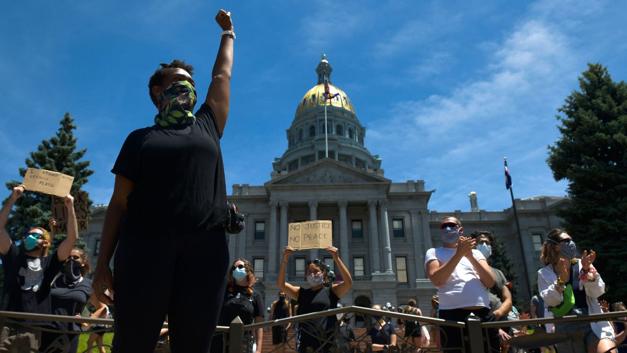 A woman at the state Capitol in Denver raises her fist during the fifth consecutive day of protests.