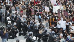 In a show of peace and solidarity, law enforcement officials with riot shields kneel in front of protesters Monday, June 1, 2020, during a fourth day of protests over the death of George Floyd in Minneapolis. (Curtis Compton/Atlanta Journal-Constitution via AP)