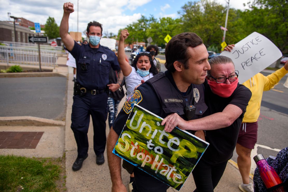 A protester and police officer walk in an embrace during a demonstration march in Connecticut.