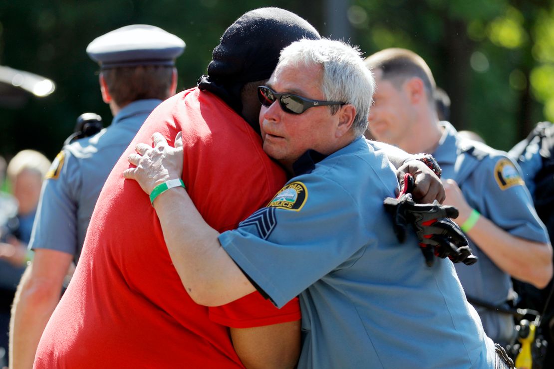 A protester and officer share an embrace. 