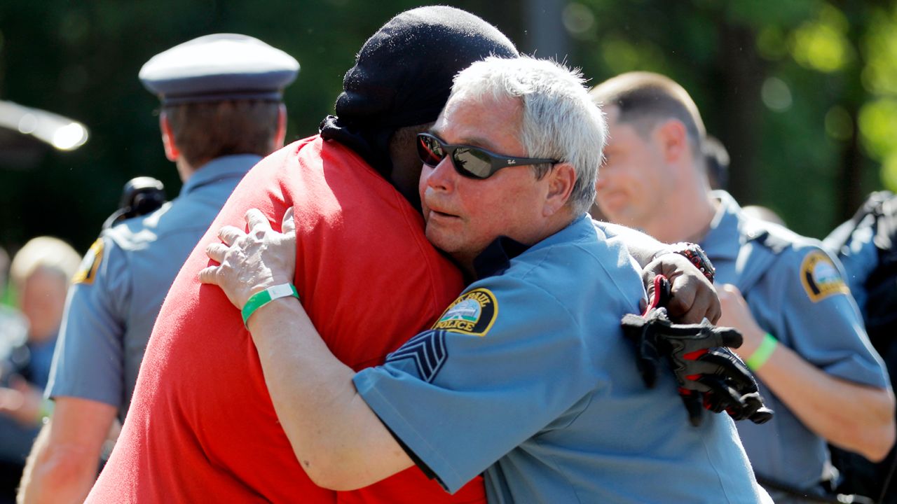 A protester and officer share an embrace. 