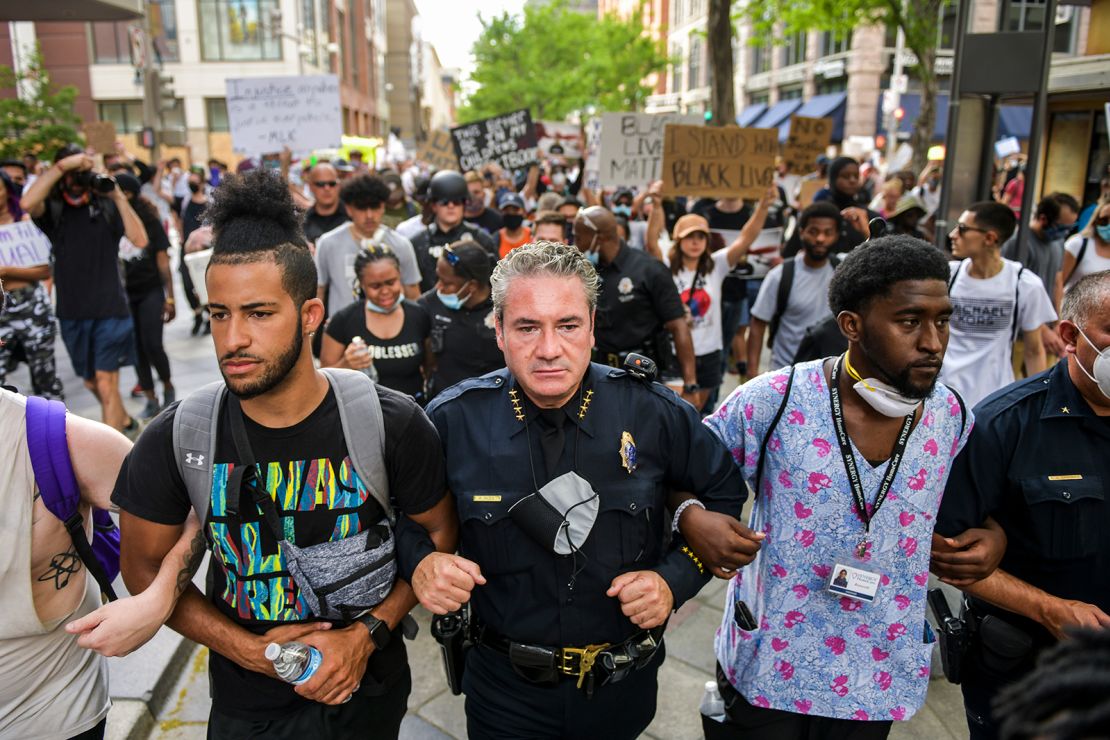 Denver Police Chief Paul Pazen links arms with people protesting.