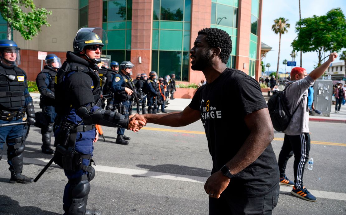 A CHP officer and protester shake hands during a demonstration.