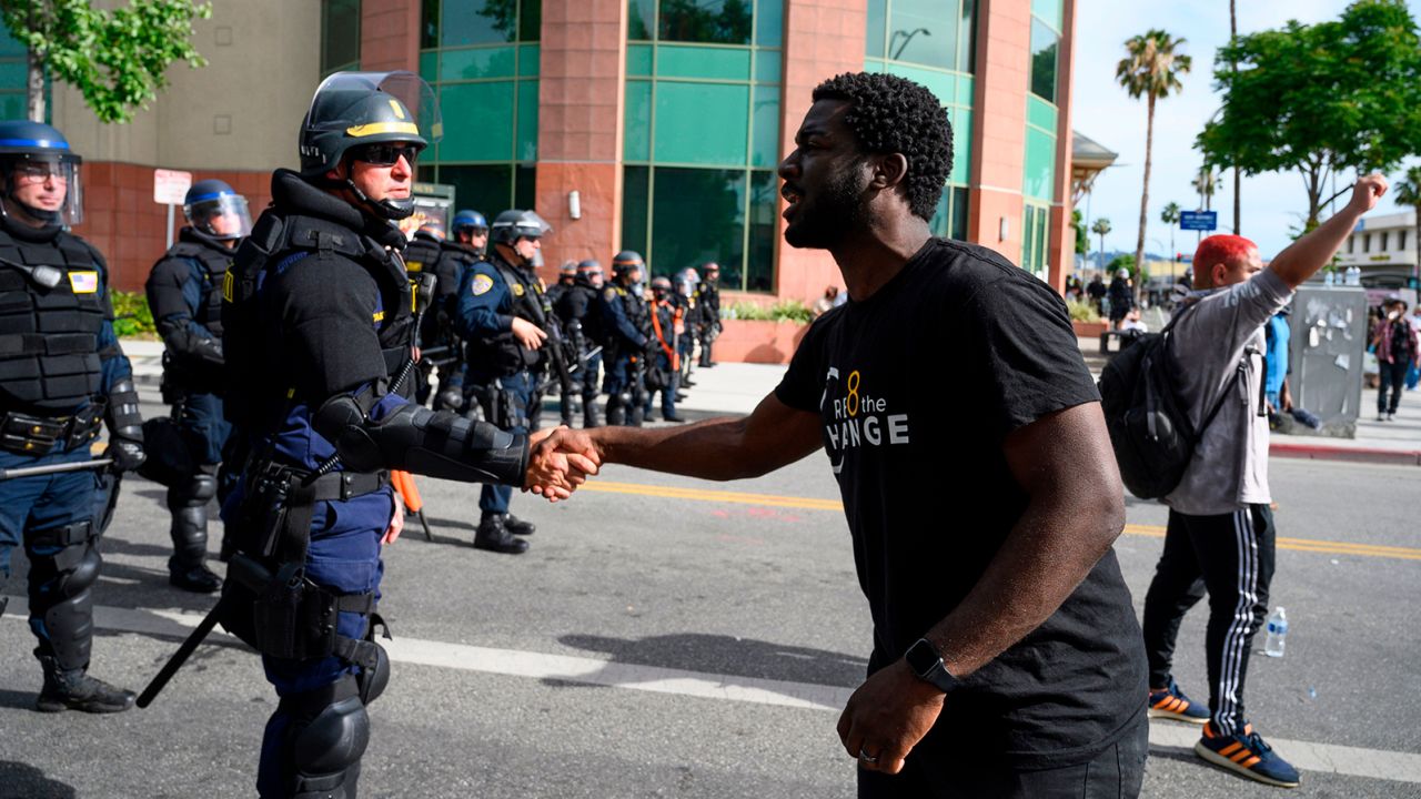 A CHP officer and protester shake hands during a demonstration.