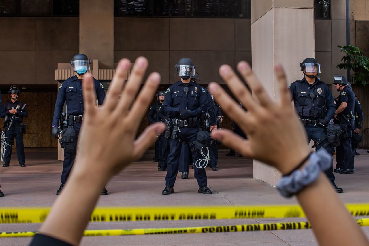 A demonstrator holds her hands up while she kneels in front of police officers at City Hall in Anaheim, California, on June 1.