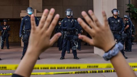 A demonstrator holds her hands up while she kneels in front of the Police in Anaheim, California, during a peaceful protest of George Floyd's killing.