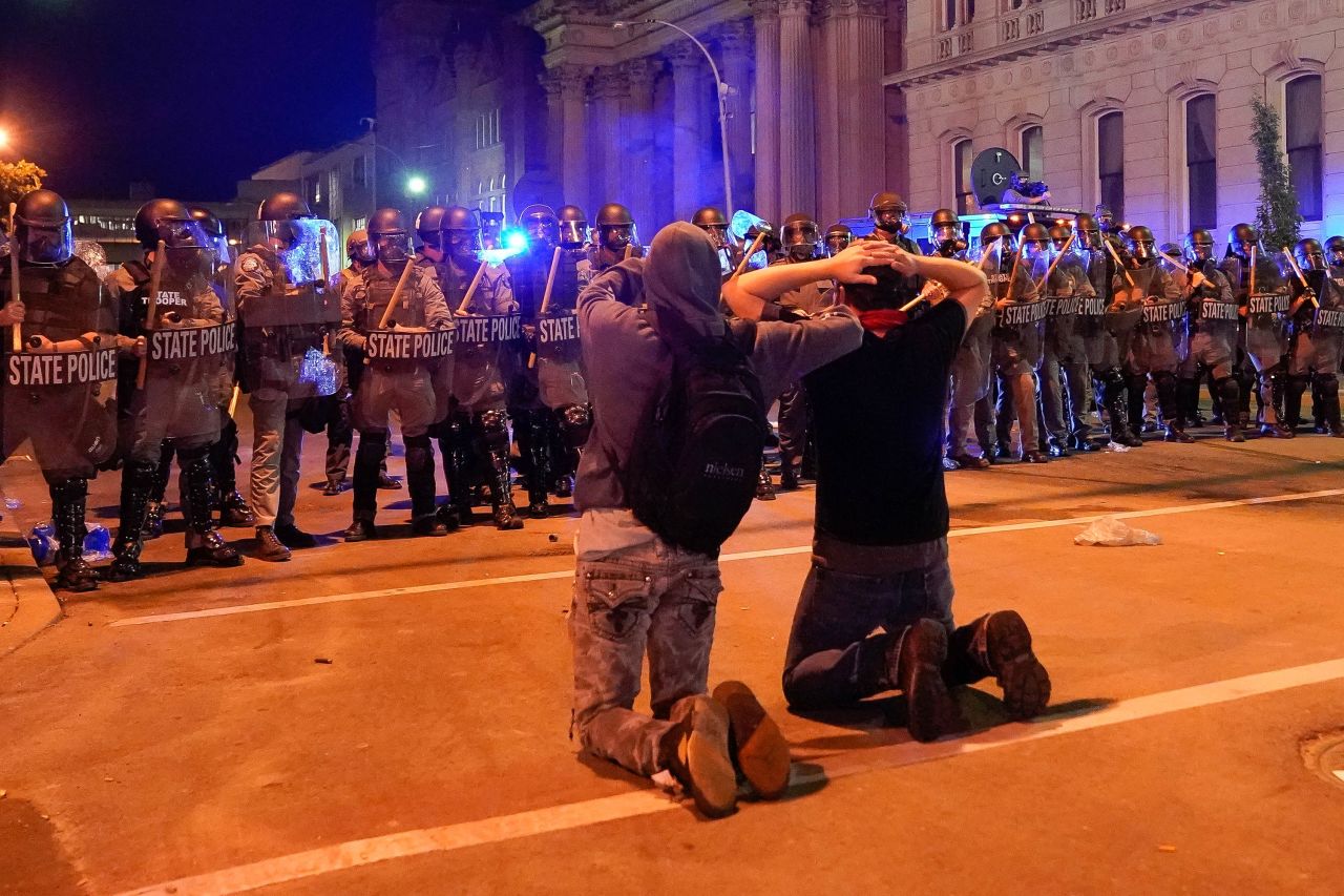 Two men kneel in front of a line of Kentucky state troopers during a protest in Louisville on June 1.