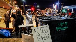 Protesters raise their hands beside a fence intended to block potential police advances at a memorial for George Floyd where he died outside Cup Foods on East 38th Street and Chicago Avenue, Monday, June 1, 2020, in Minneapolis. Protests continued following the death of  Floyd, who died after being restrained by Minneapolis police officers on May 25. (AP Photo/John Minchillo)