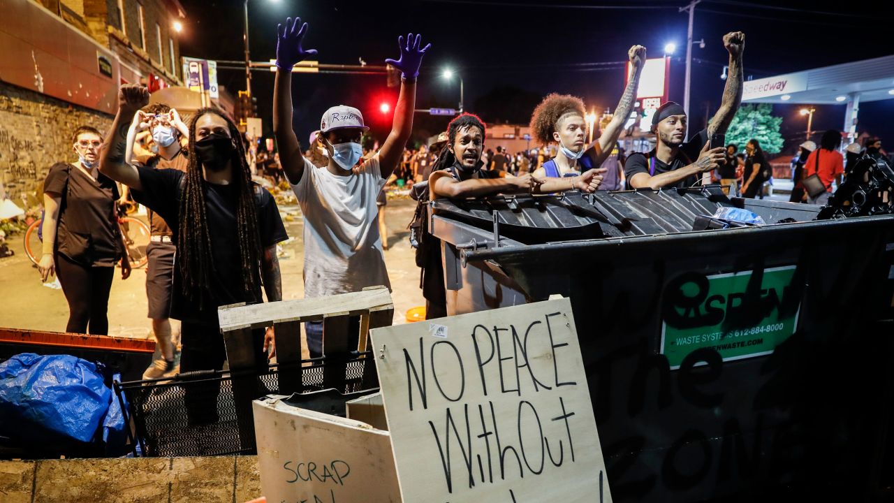 Protesters raise their hands beside a fence intended to block potential police advances at a memorial for George Floyd where he died outside Cup Foods on East 38th Street and Chicago Avenue, Monday, June 1, 2020, in Minneapolis. 