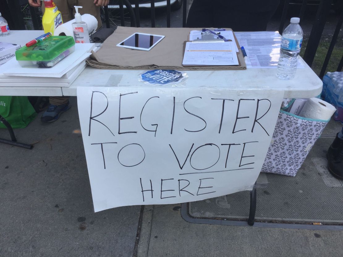 A table on a sidewalk in sidewalk gave protests an opportunity to register to vote.