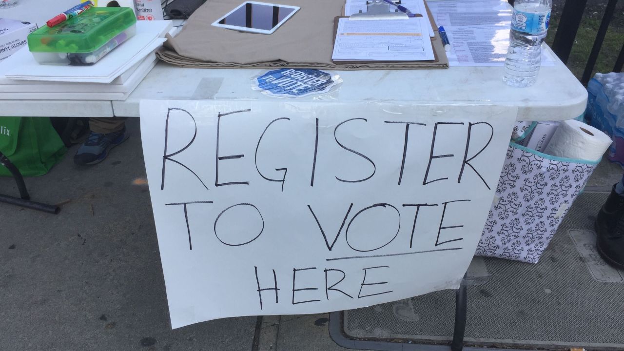 A table on a sidewalk in sidewalk gave protests an opportunity to register to vote.