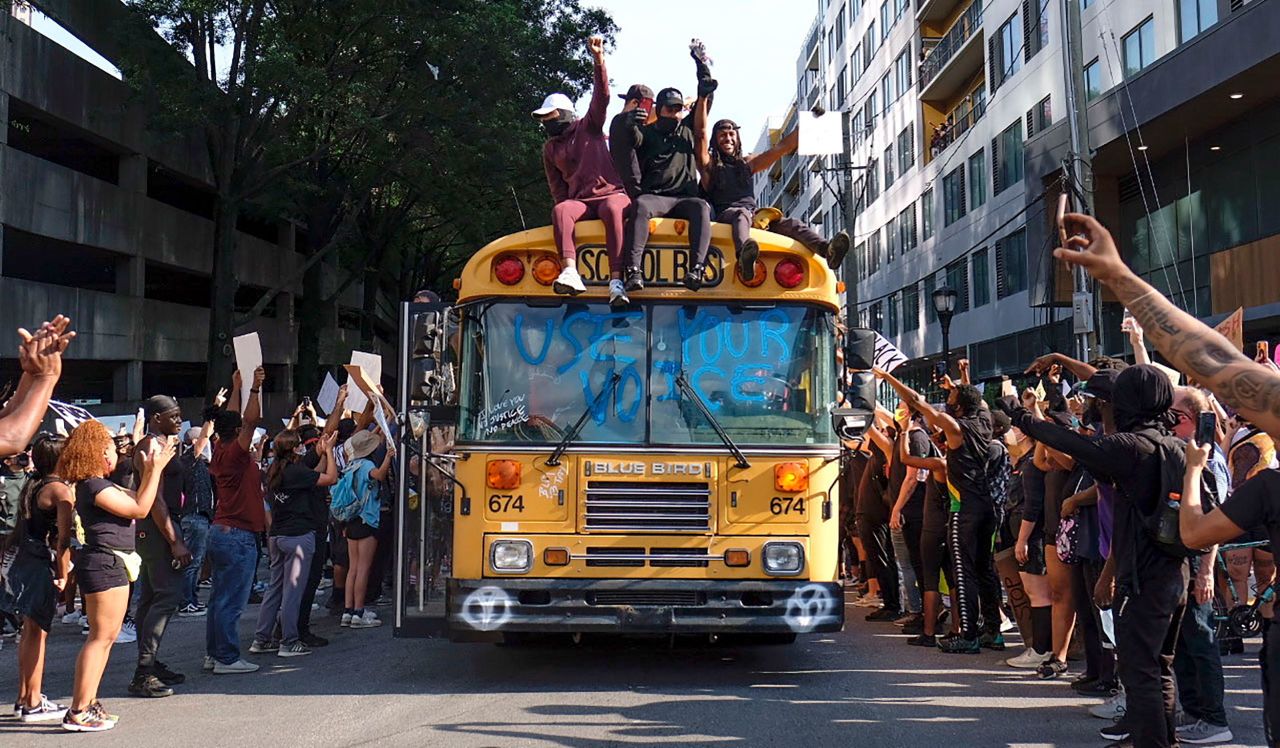 Protesters ride a bus through a street in Atlanta on June 2. The windshield reads "use your voice."