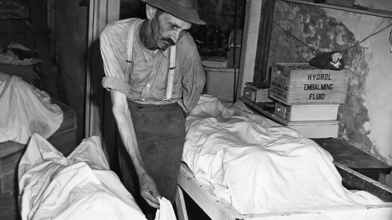 Coroner W.T. Brown places a sheet over the body of one of four Moore's Ford lynching victims in 1946.