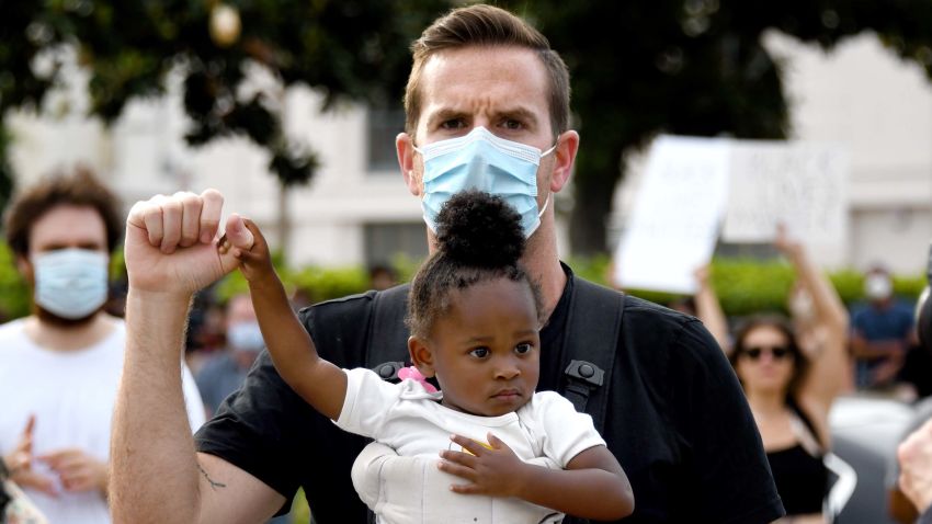 PASADENA, CA - JUNE 02:  Eric Puestow of Pasadena with his 1 1/2 year-old daughter Simone holds his fist up as she holds onto his hand as thousands of demonstrators caravaned to the Pasadena City Hall to protest and hold a vigil after the death of George Floyd, a black man who was in police custody in Minneapolis in Pasadena on Tuesday, June 2, 2020. (Photo by Keith Birmingham/MediaNews Group/Pasadena Star-News/Getty Images)