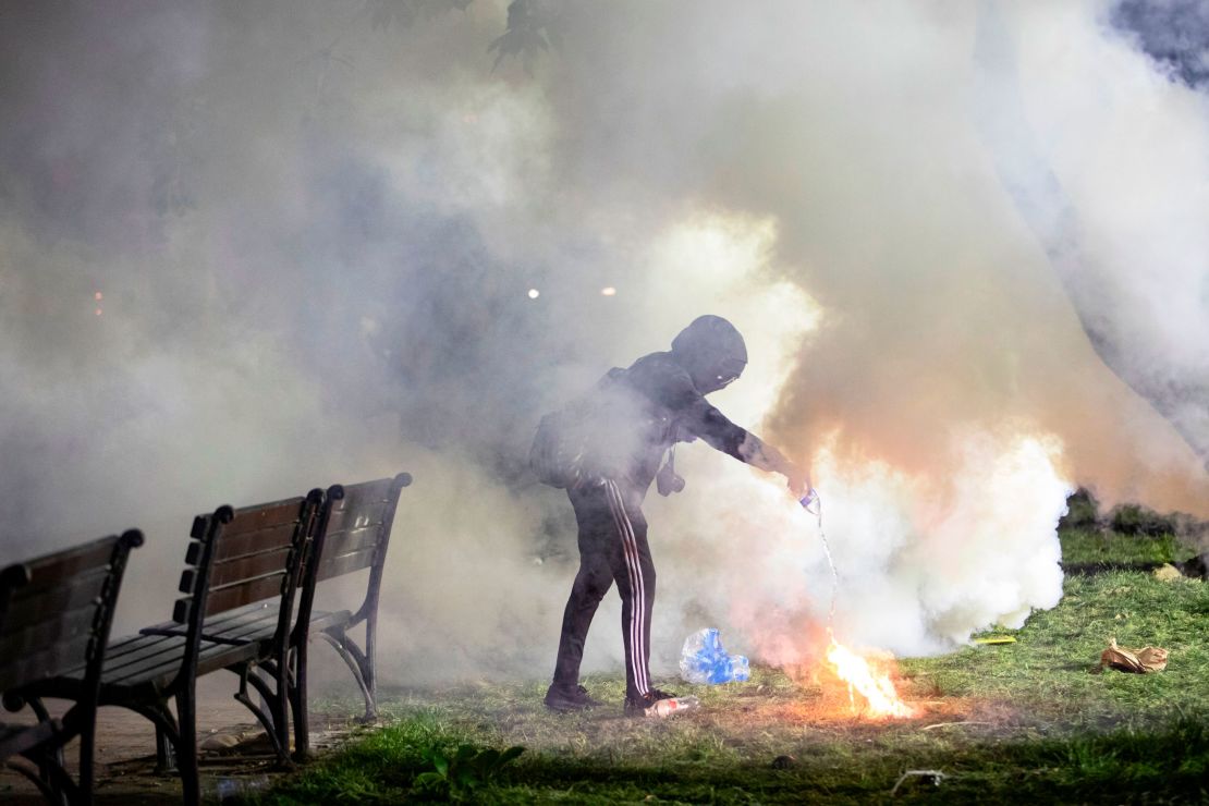 A demonstrator pours water on a tear gas canister in front of the White House on May 31, 2020. - Police fired tear gas outside the White House late Sunday as major US cities were put under curfew to suppress rioting as anti-racism protestors again took to the streets to voice fury at police brutality. 