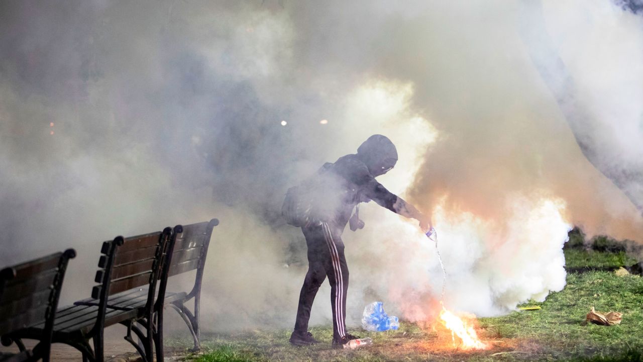 A demonstrator pours water on a tear gas canister in front of the White House on May 31, 2020. - Police fired tear gas outside the White House late Sunday as major US cities were put under curfew to suppress rioting as anti-racism protestors again took to the streets to voice fury at police brutality. 